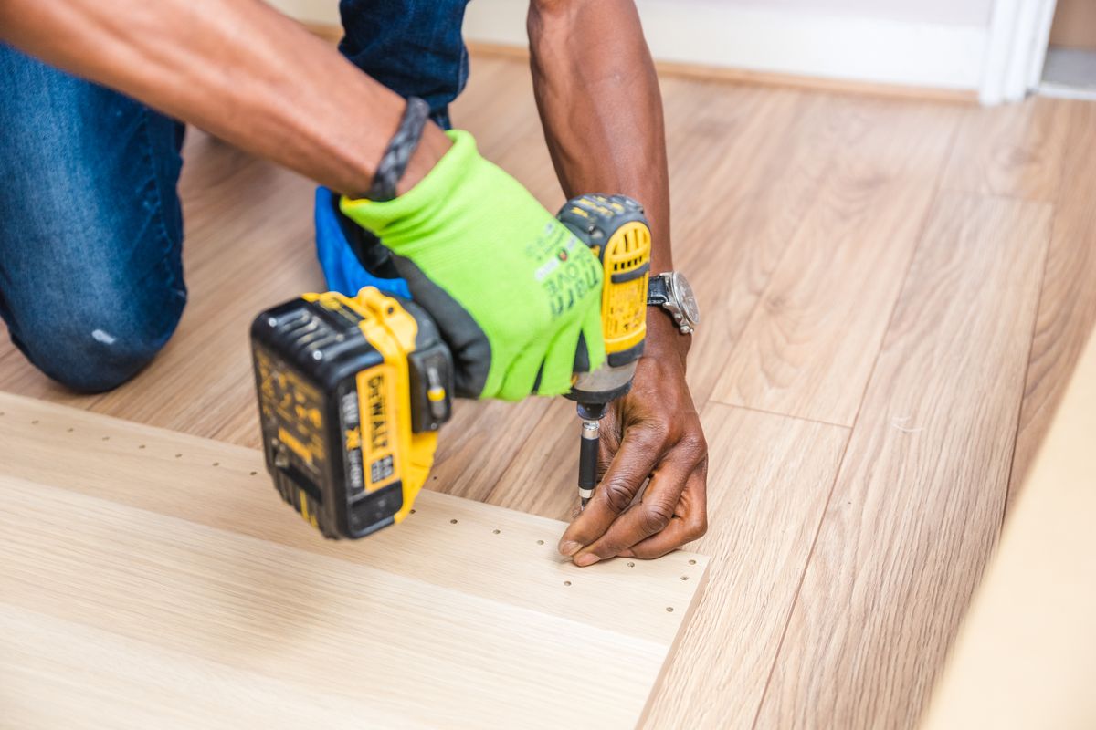 Person holding a cordless drill with a battery pack