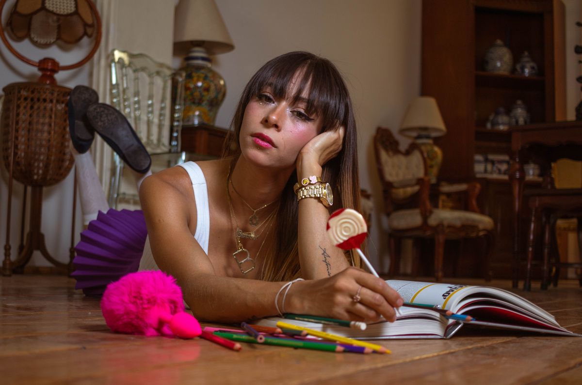 A relaxed woman with a lollipop lying on the floor with a coloring book, vibrant and casual indoor setting.