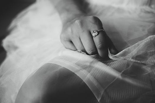 Elegant close-up of a woman's hand holding delicate fabric, showcasing a stylish ring.