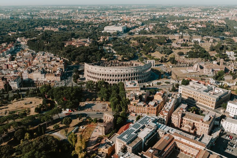 An expansive aerial view of Rome highlighting the iconic Colosseum amidst the historic cityscape.