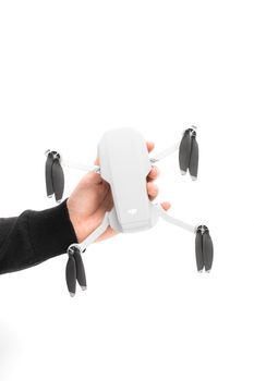 Close-up of a compact drone held in a hand against a white background, emphasizing technology.
