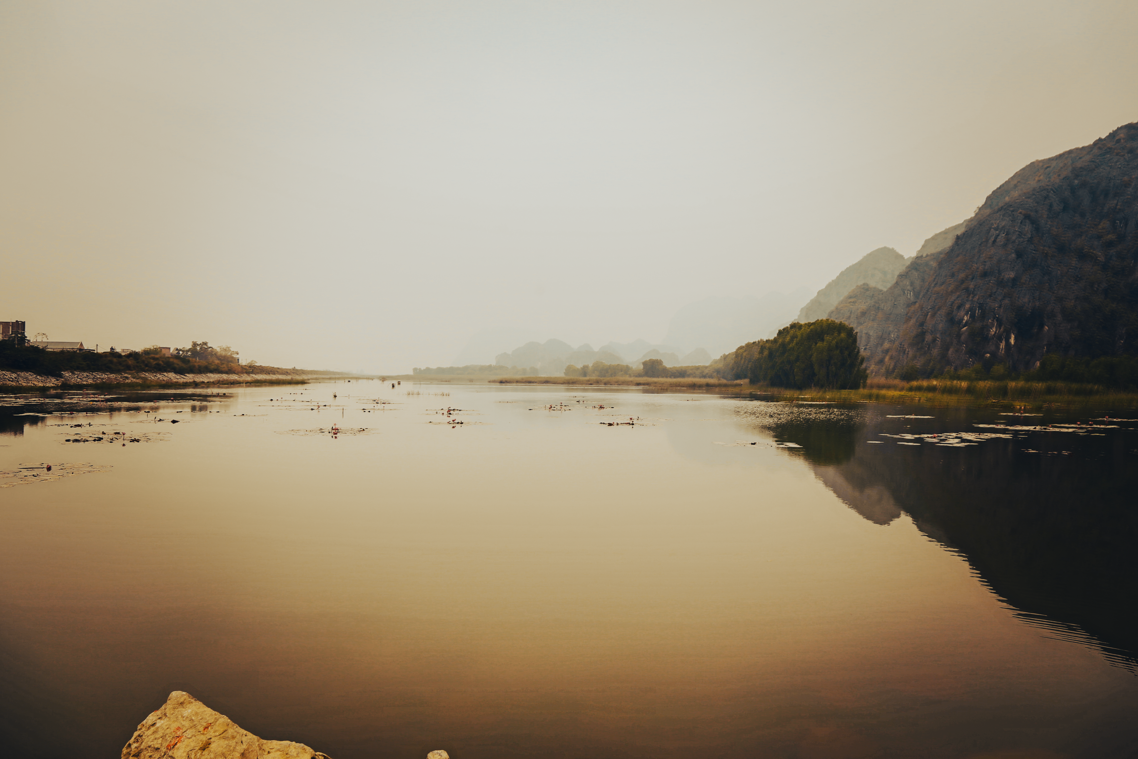 Tranquil scene of a fog-covered lake with mountains reflecting in the water.