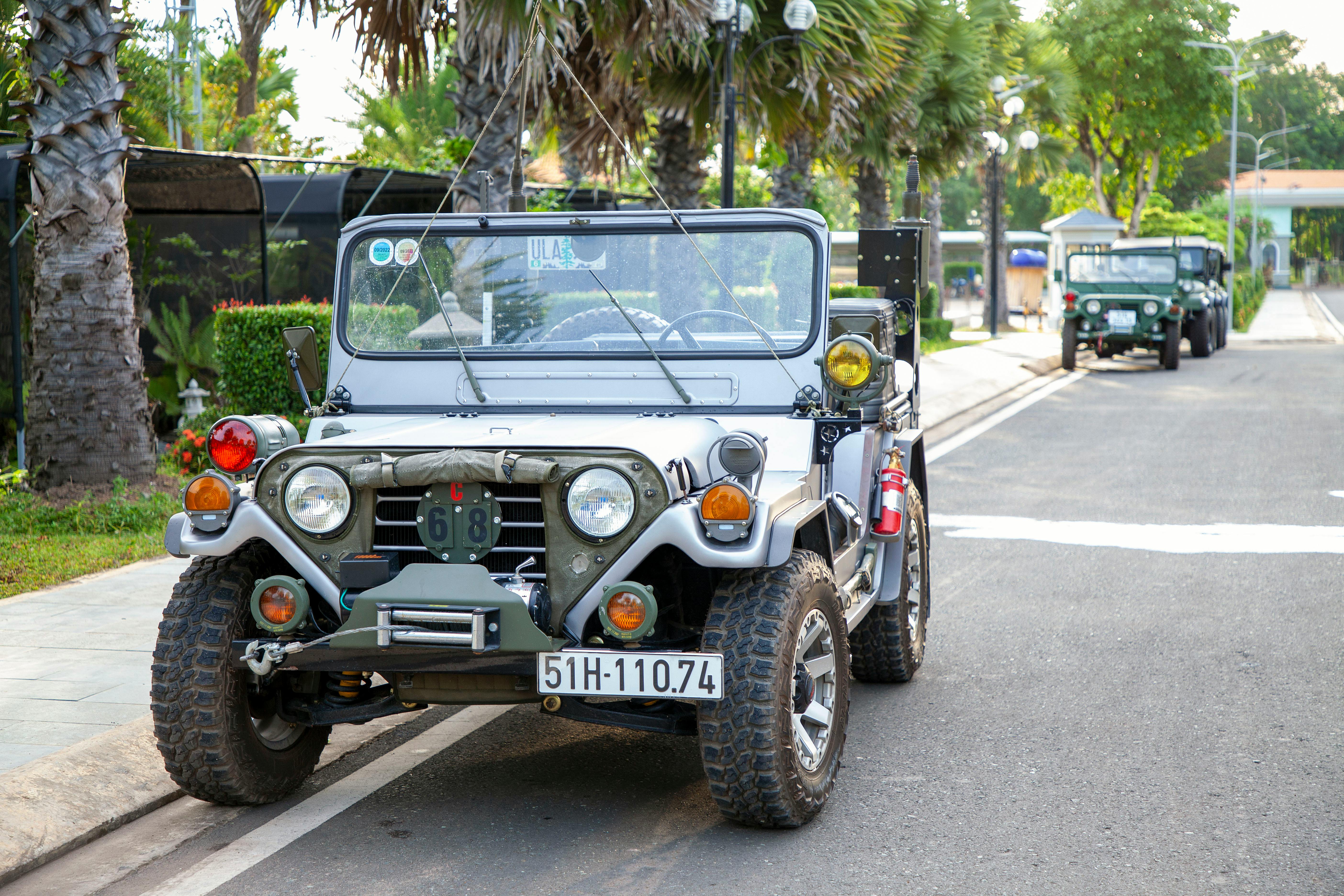 Vintage jeep parked on a scenic street with trees, evoking adventure and exploration.
