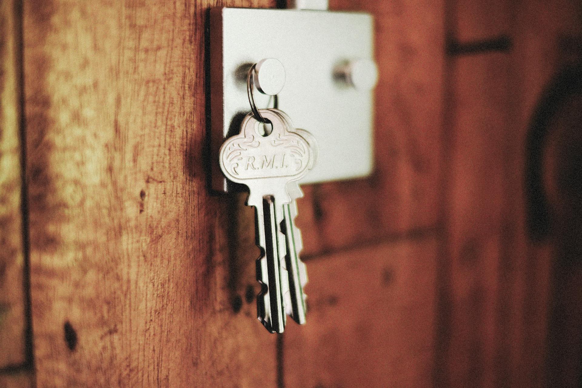 Detailed shot of keys hanging in a door lock on a wooden surface, warm tones.