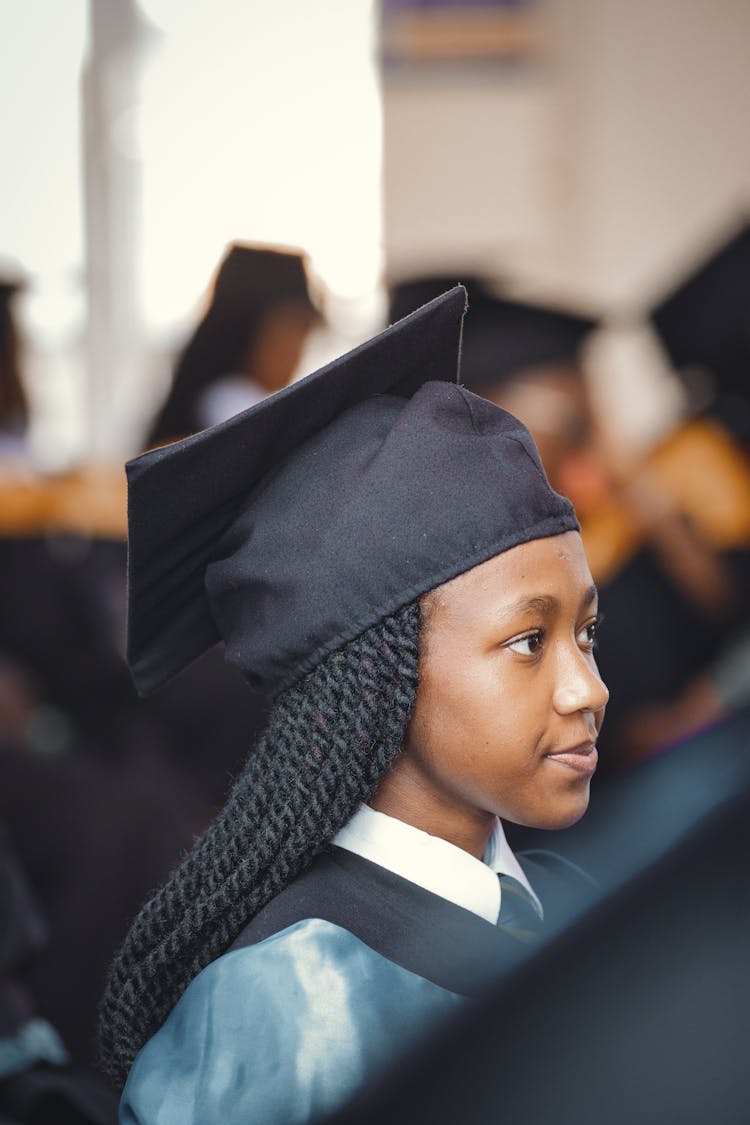 Woman In A Graduation Gown Listening To A Speech 