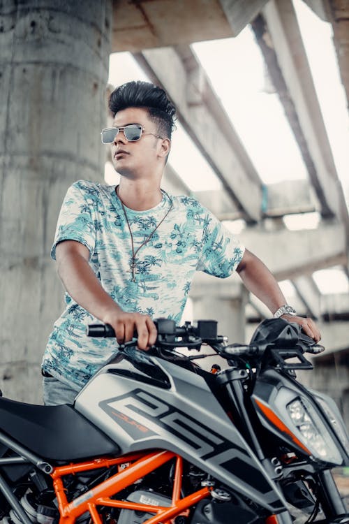 Photo of a Young Man Standing next to Motorcycle