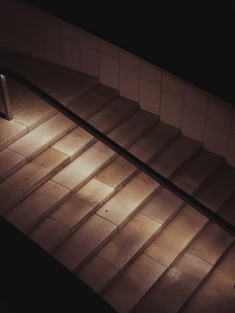 Capture of a dimly lit stairway in an urban setting at night, showcasing architectural lines and shadows.