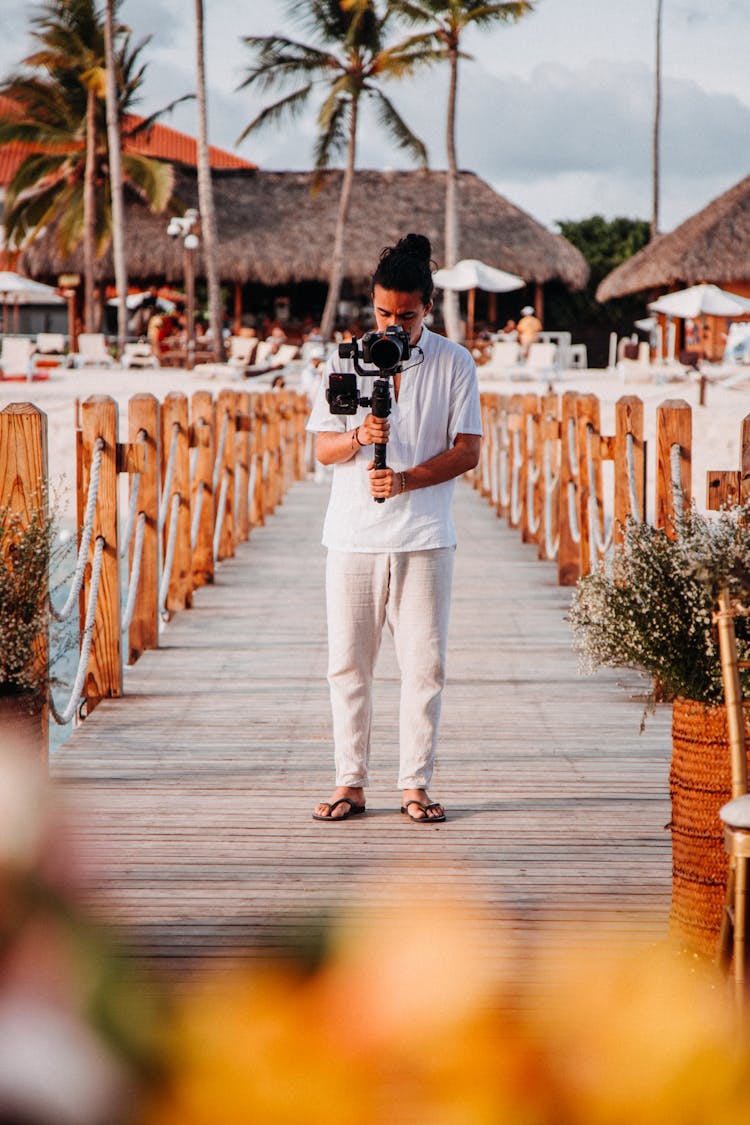 Man Holding Professional Camera Filming On Beach