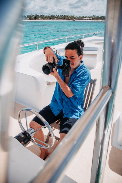 A Man Sitting on the Yacht using a Camera 