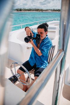 Man taking a photo on a boat with a camera. Vibrant ocean and sky backdrop.