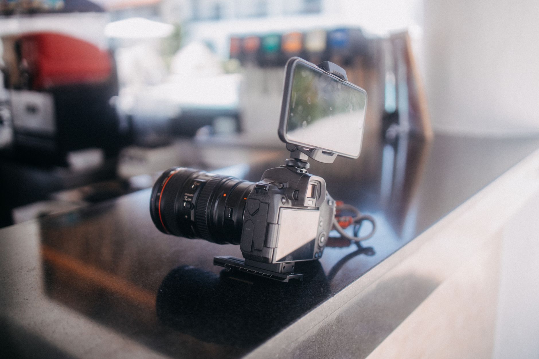 Mirrorless camera with external screen on a granite kitchen counter in soft lighting.