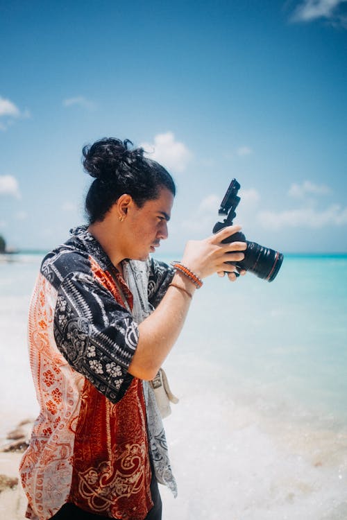 A Man Standing Near Body of Water Holding a Camera