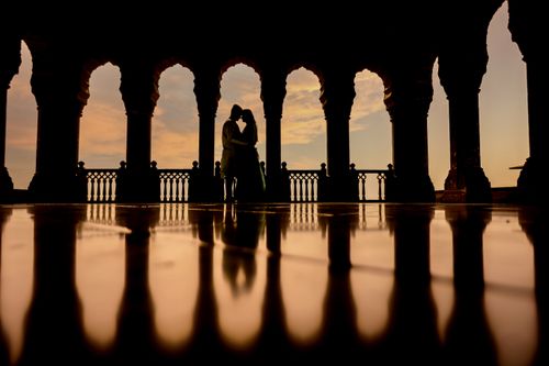 Free Silhouette of a couple embracing in historic Indian arches at sunset, symbolizing love and romance. Stock Photo