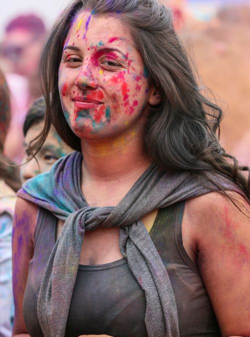 Free A woman joyfully participates in a Holi festival, covered in bright colorful powders. Stock Photo