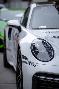 Close-up shot of a sleek sports car with white livery, showcasing its modern headlight design.