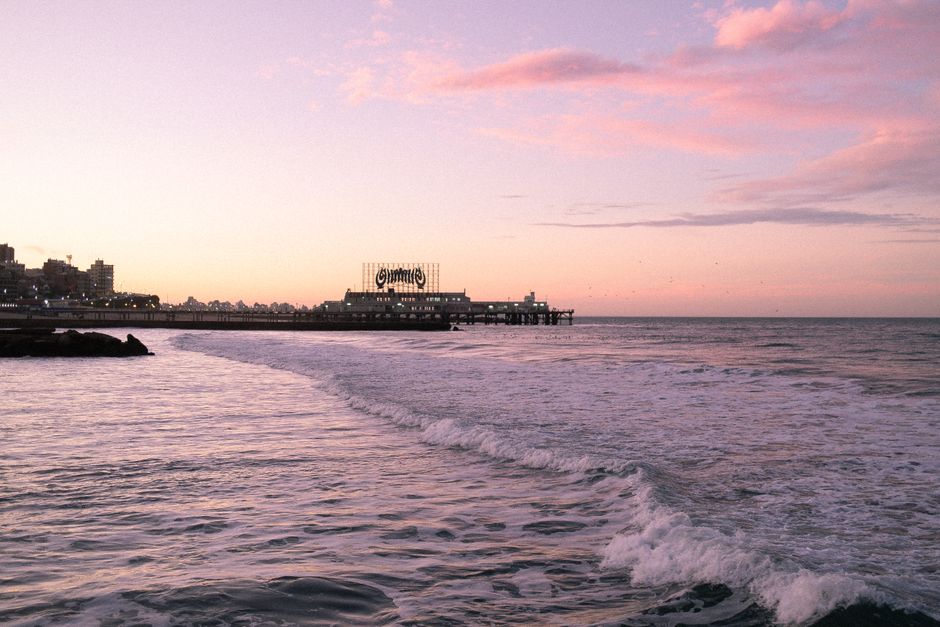 Beautiful sunset view at Mar del Plata beach, Argentina with ocean waves and pier silhouette.