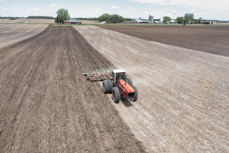 Red Farm Tractor Plowing The Field