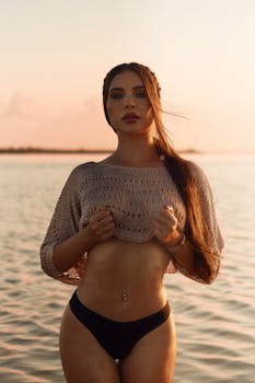 Brunette woman in knitwear at the beach during sunset, exuding a serene and fashionable vibe.