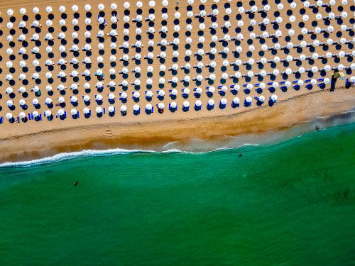 Free Vibrant aerial view of beach umbrellas lined up on Sozopol beach in Bulgaria's summer coast. Stock Photo