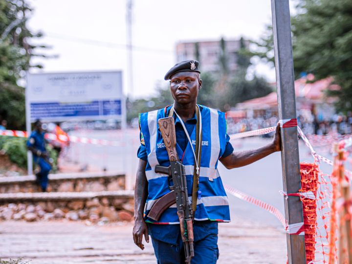 Armed security officer in a reflective vest standing guard at a roadside checkpoint