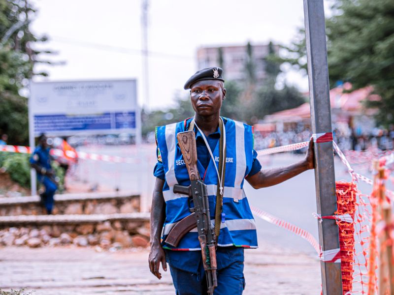 Armed security officer in a reflective vest standing guard at a roadside checkpoint