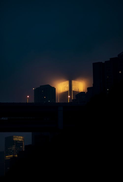 Free A striking cityscape at night with illuminated urban buildings glowing in the dark sky. Stock Photo