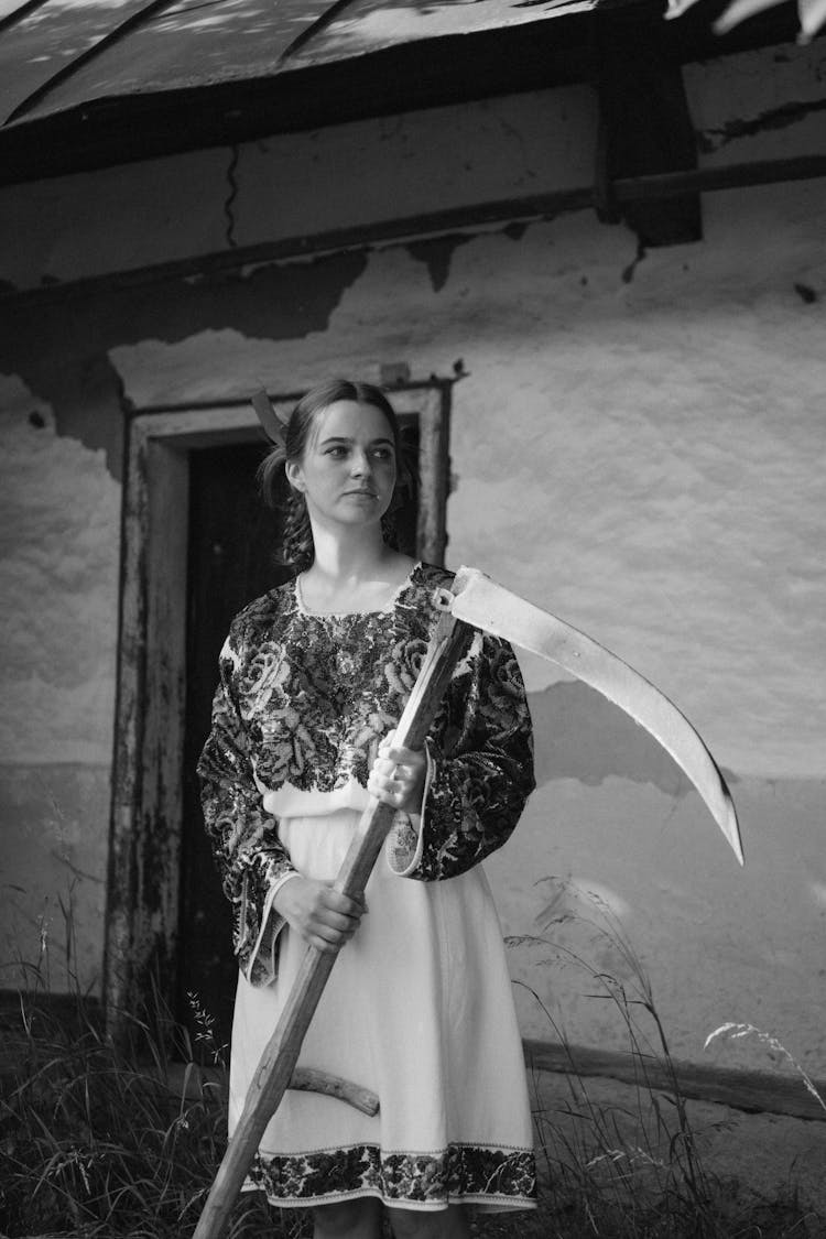 Woman In Traditional Clothes Holding Scythe