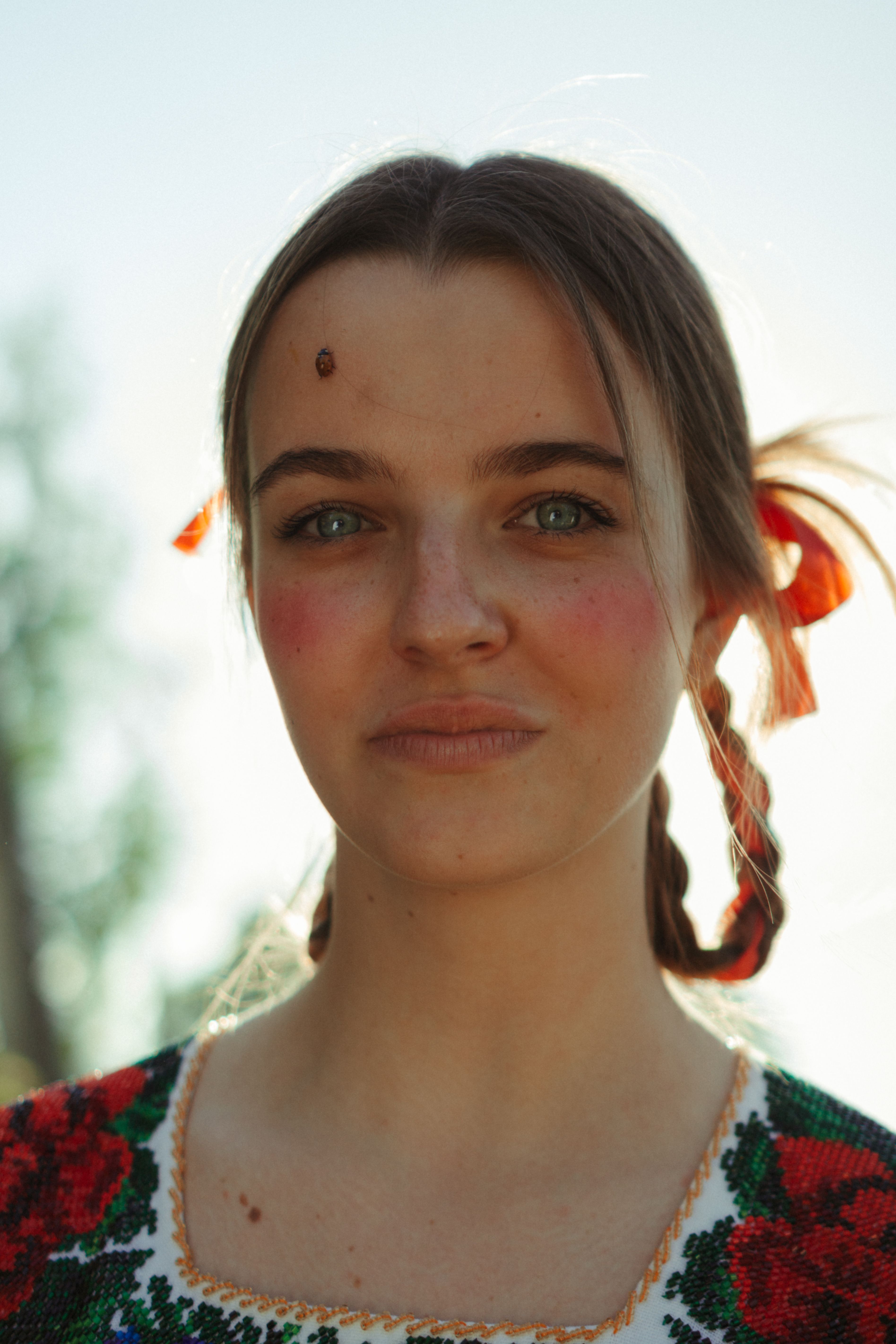 Young woman with traditional attire and braided hair, posing outdoors.