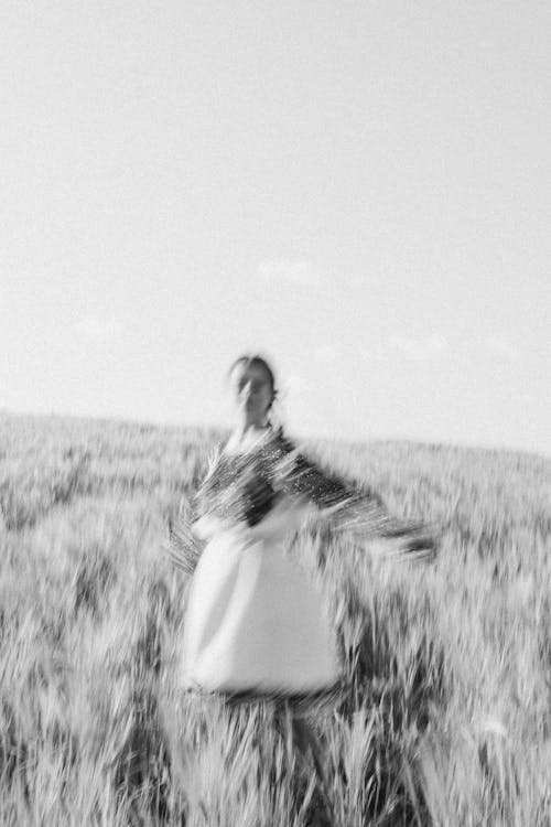 Free Grayscale Photo of Woman in Dress Standing on Grass Field Stock Photo