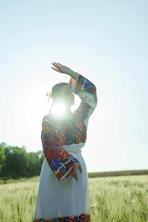 Woman Wearing a Floral Dress Standing in the Middle of a Grass Field
