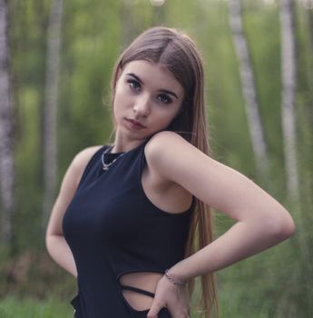 Portrait of a young woman standing elegantly in a lush birch forest, creating a serene and natural backdrop.