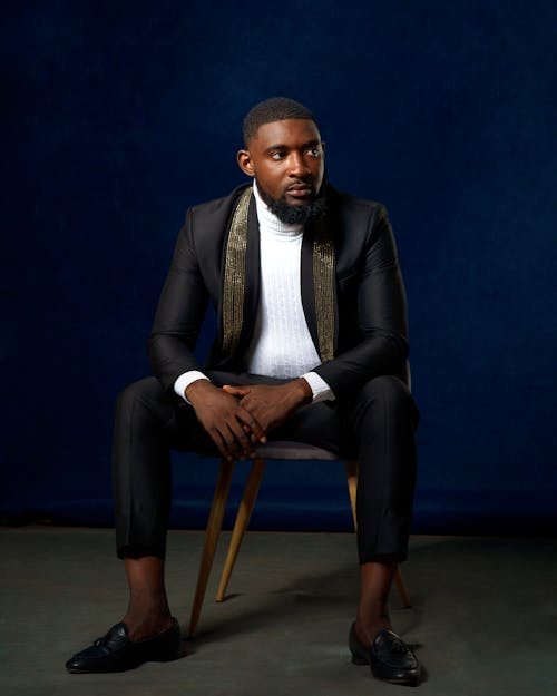 Man in Black Suit Sitting on Brown Wooden Chair