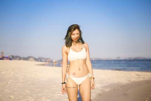 Free Woman in a bikini at the beach, enjoying a sunny day by the seashore. Stock Photo