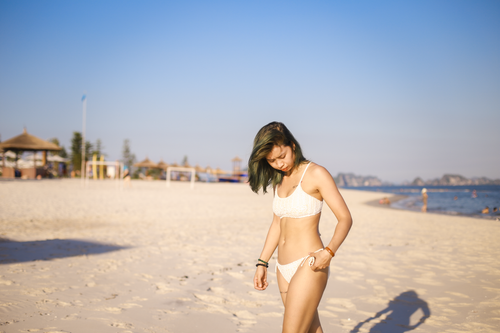 Free Young woman walking on a sunny beach in a bikini, enjoying the day. Stock Photo