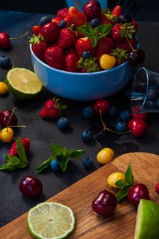 A colorful display of fresh berries and lime on a dark table, perfect for food photography.