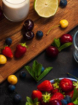 A vibrant display of fresh berries and fruits with mint on a wooden table, perfect for healthy eating concepts.