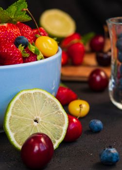 Close-up of a vibrant bowl filled with fresh strawberries, blueberries, cherries, and a lemon slice.