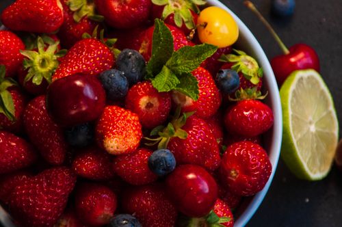 Free A colorful assortment of fresh strawberries, blueberries, cherries, and lime in a bowl, perfect for summer. Stock Photo