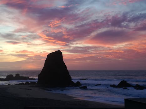 Stunning sunrise at a beach in Santa Cruz, Madeira, Portugal with vibrant skies and rock formations.