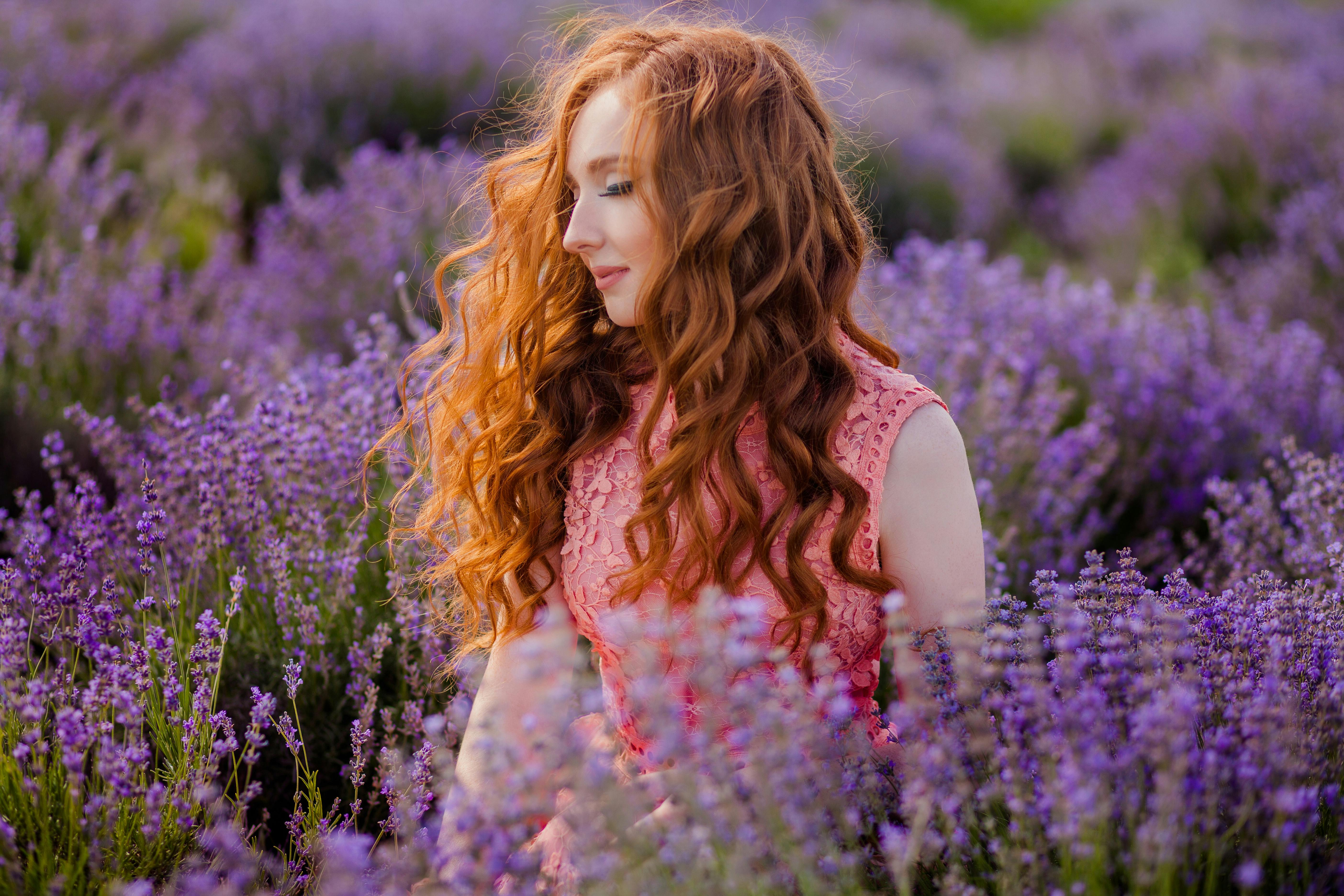Portrait of a redhead woman surrounded by vibrant lavender flowers in a summer field.