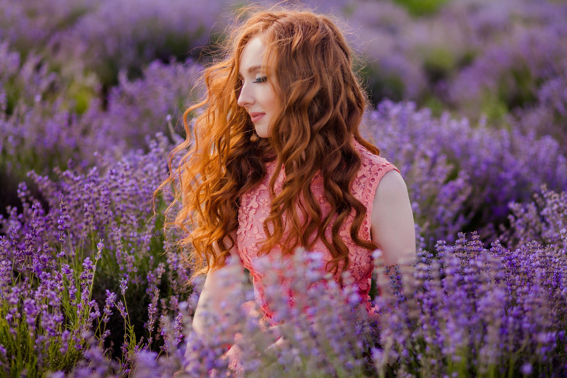 Portrait of a redhead woman surrounded by vibrant lavender flowers in a summer field.