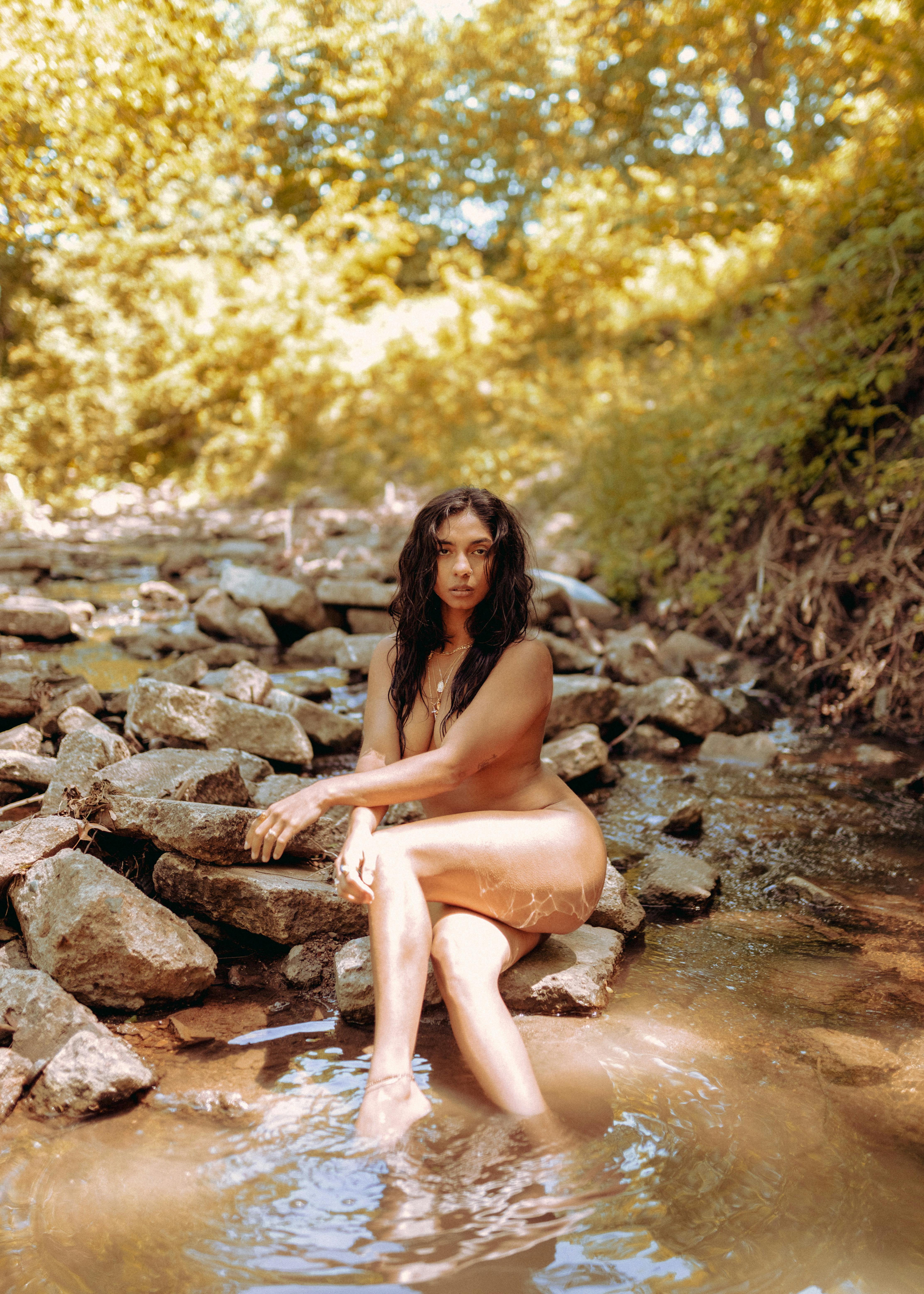 naked woman sitting on rock