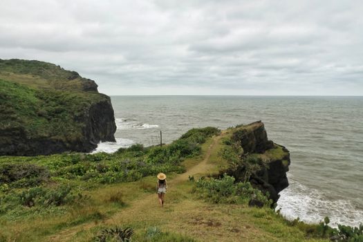 A woman walks alone on a scenic cliffside path at Punta Roca Partida, Mexico.