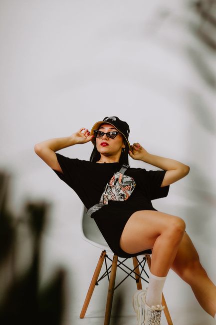 Fashionable woman posing indoors with bucket hat and sunglasses, showcasing a modern style.