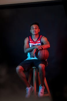 A young athlete posing with a basketball in a dramatic studio photoshoot.