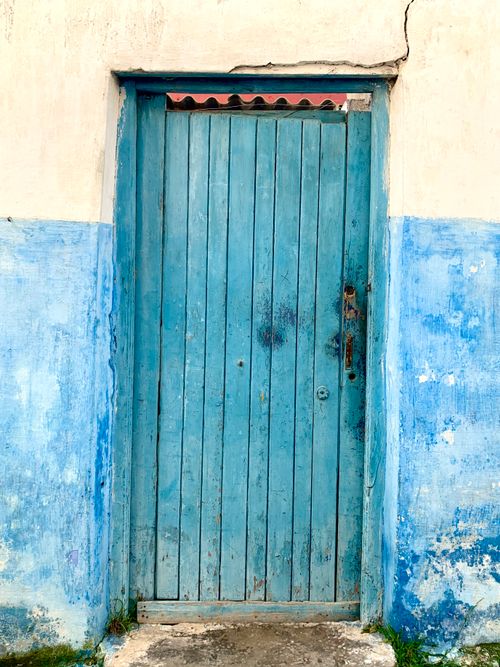 Free Rustic weathered blue wooden door in a vintage plaster wall adds a charming touch. Stock Photo