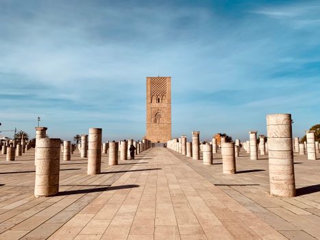 Explore the historic Hassan Tower amidst ancient columns under a clear blue sky in Rabat, Morocco.