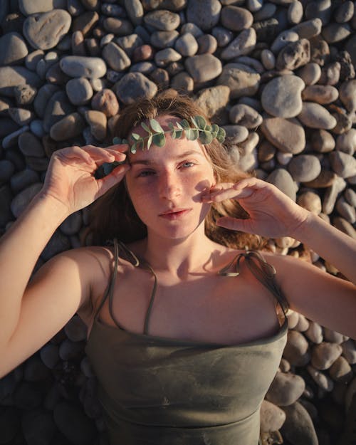 Portrait of Young Woman in Wreath Lying on Stone Beach