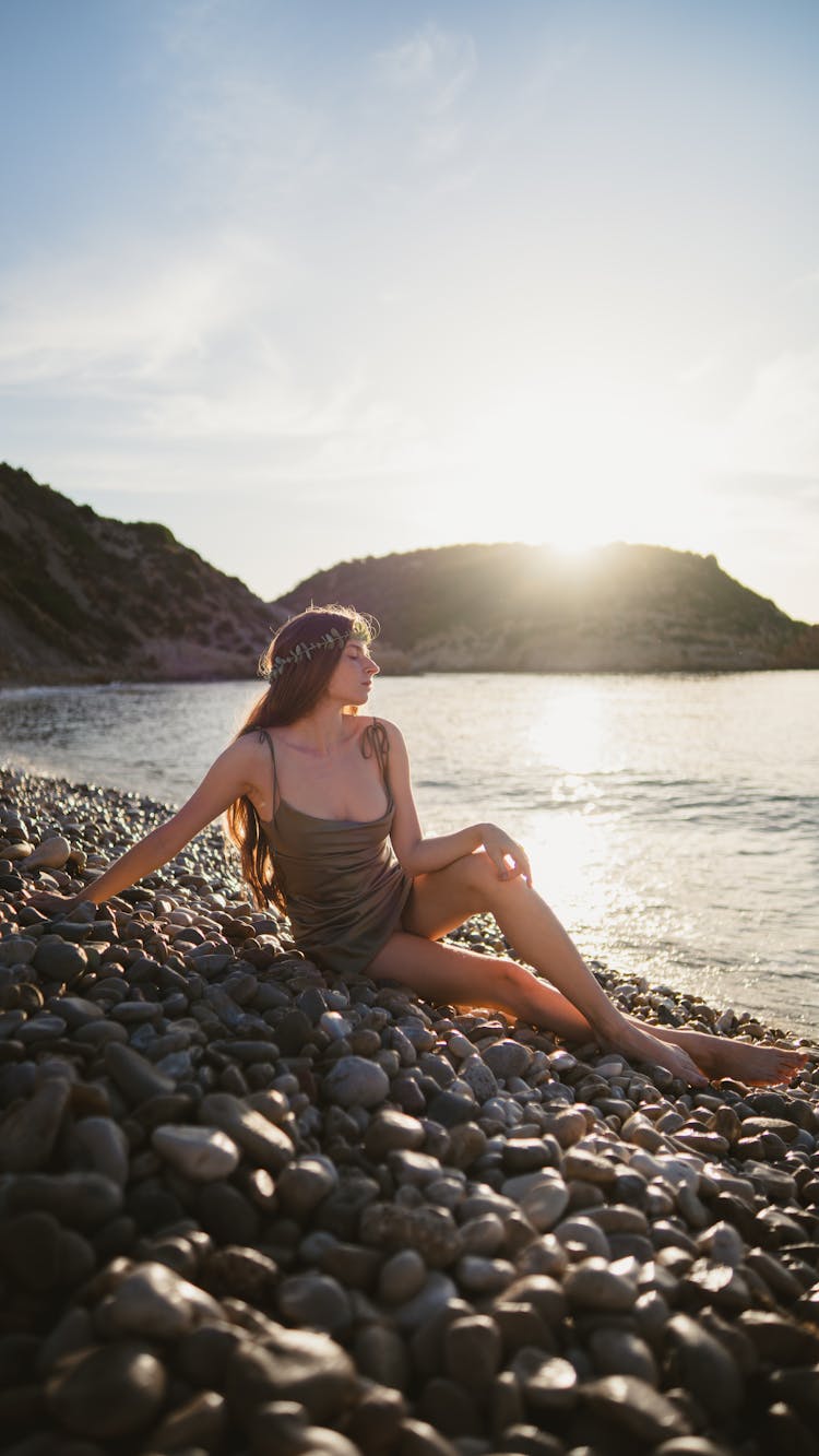 Girl Sitting On Stone Beach On Sunset