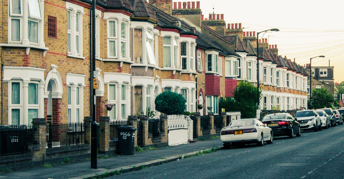 Charming view of traditional London terraced houses and parked cars along a quiet street at dusk.